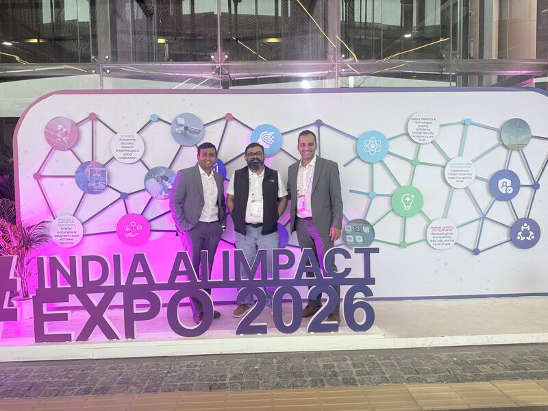 The KissanAI co-founders at the India AI Impact Expo signage on the Summit floor.
